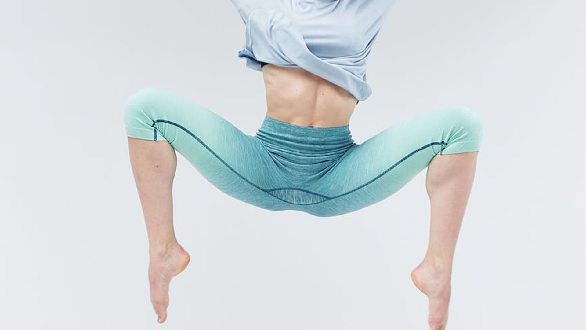 Person doing dynamic cardio movements in a dark studio.