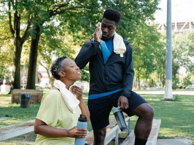 Sports bottle and towel on a dark wooden bench.